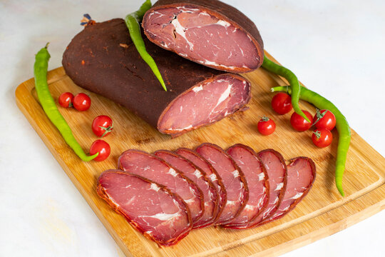 Turkish pastrami on a white background. Whole and sliced pastrami. pastrami is made from the ribeye and beef fillet parts of the cow. Local name pastırma