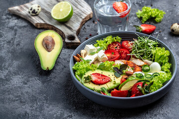 Healthy dinner. Buddha bowl lunch with grilled chicken and avocado, feta cheese, quail eggs, strawberries, nuts and lettuce. Healthy food trend. Top view