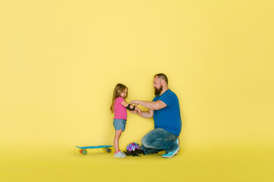 Dad helps young daughter with elbow pads