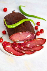 Turkish pastrami on a white marble background. Whole and sliced pastrami. Pastrami is made from the ribeye and beef fillet parts of the cow.