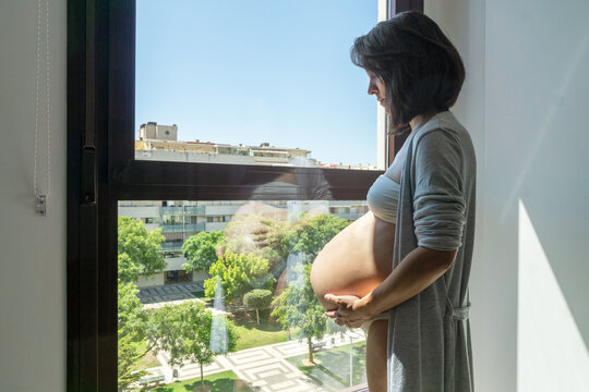 Pregnant young woman in front of a window in her bedroom
