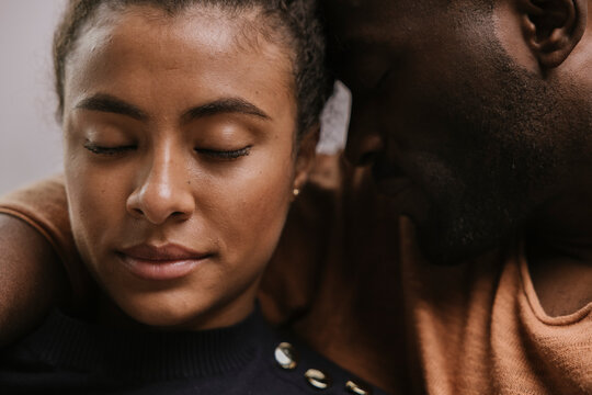 Tender black couple hugging with closed eyes