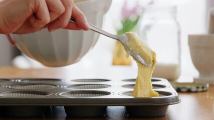culinary, bake and people concept - happy smiling young woman cooking food on kitchen at home putting batter in baking dish for cupcakes