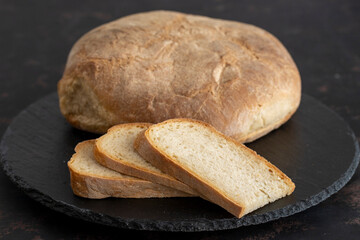 Organic round bread on a dark wooden background. Sliced bread. Traditional sourdough bread