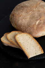 Organic round bread on a dark wooden background. Sliced bread. Traditional sourdough bread