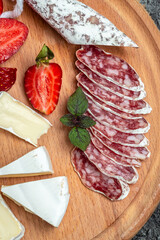 Spanish Fuet salami wurst with Camembert cheese, strawberries. Food recipe background. vertical image. top view