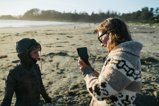 Mom taking photo of girl covered in sand