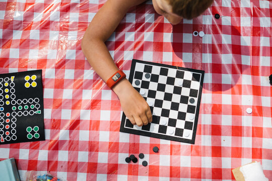 Boy playing checkers with friend on campsite
