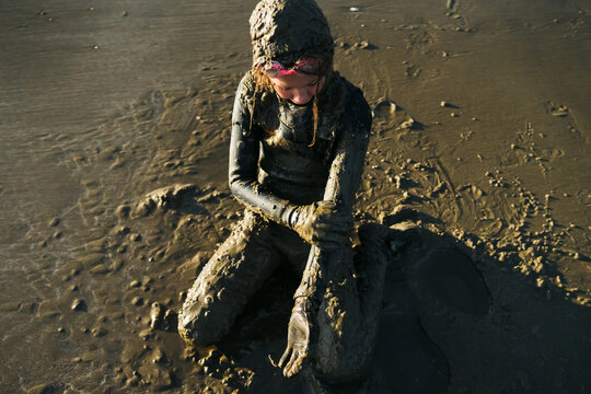 Girl in wetsuit covered in sand