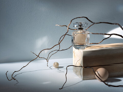 glass perfume bottle on a wooden plate on a light background