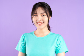 Young asian girl in cyan shirt using phone on purple background