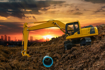 Excavator is digging in the construction site pipeline work on sunset sky at cityscapes background - obrazy, fototapety, plakaty