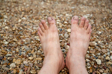 Bare feet of a man on the beach close up