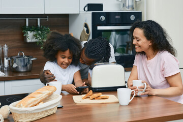 Positive family with a child spend time together in a kitchen while cooking - obrazy, fototapety, plakaty