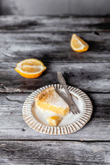 Slice of lemon pie on white ceramic plate, grey wooden background, selective focus, copy space