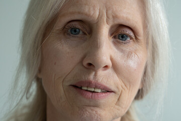 Close-up of the face of an elderly woman with gray hair, looking at the camera