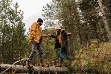 Couple walking on top of fallen tree in forest