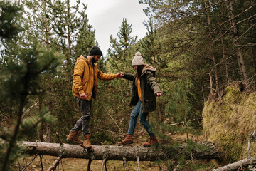 Couple walking on top of fallen tree in forest