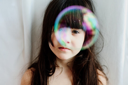 Portrait of a child girl with a soap bubble on face 