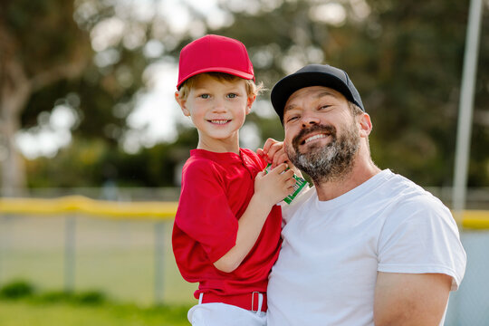 Proud dad holding son at little league game