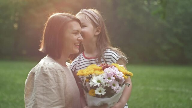 Little girl gives flowers to her mother. Lovely family together. Summer day. Family portrait. Happy motherhood. Enjoy nature. Mothers Day.