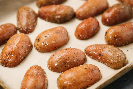 Oiled and seasoned raw fingerling potatoes ready for roasting