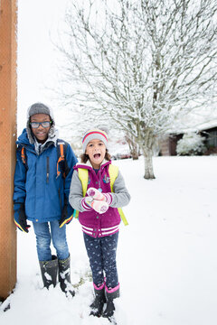 siblings stand in snow at bus stop