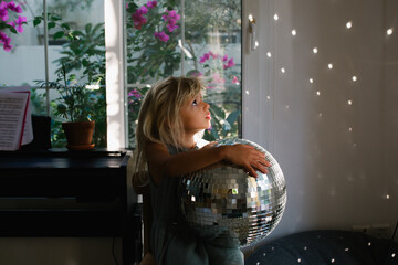A little girl with a glass ball and light coming from it