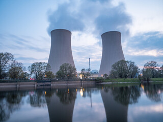 Nuclear power plant against sky by the river at sunset