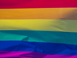 Rainbow flag in sunshine against blue sky