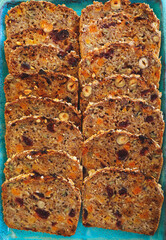 A piece of bread with dried fruits on blue plate, dried apricots, raisins, prunes and hazelnuts, top view.