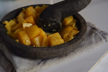 selective focus of fried potato mashed in a stone bowl named cobek