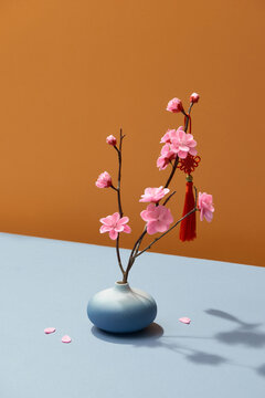 Beautiful pink blossoming peach trees in vase over color background with reflection