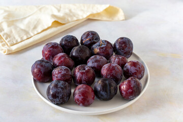 Ripe fresh damsons on a white ceramic plate