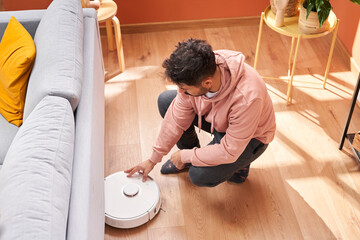 Man turning on robotic vacuum cleaner
