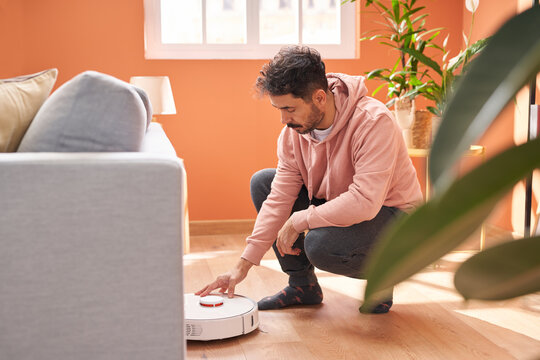 Man pushing button on robotic vacuum cleaner