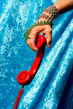 man with the handset of a red telephone in his hand