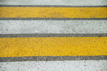 Crosswalk on the street in the city. Yellow and white stripes on the gray asphalt.