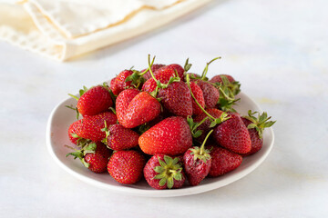 Ripe fresh strawberries on a white ceramic plate