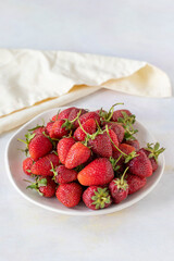 Ripe fresh strawberries on a white ceramic plate