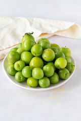 Ripe fresh green plums on a white ceramic plate