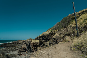 A dike (American spelling) or dyke (British spelling), in geological usage, is a sheet of rock that is formed in a fracture of a pre-existing rock body. Kaena ponit trail, Oahu, Hawaii.