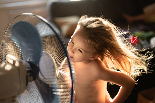 Toddler girl playing in front of the fan