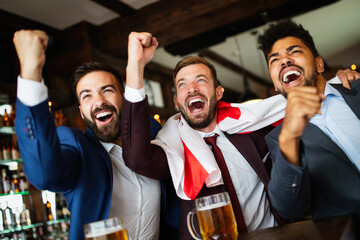 Group of friends at the pub watcing football game and drinking beer