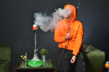 Obraz premium man smoking fruit hookah on table in hookah lounge