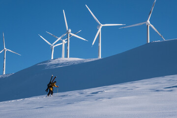 wind genarators, snow, and man carrying skis