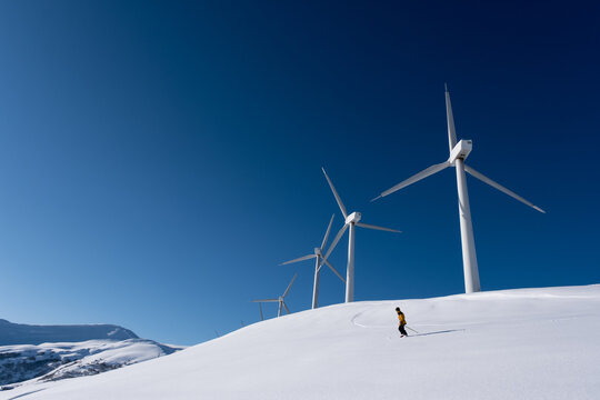 a  person skiing under wind turbines. 