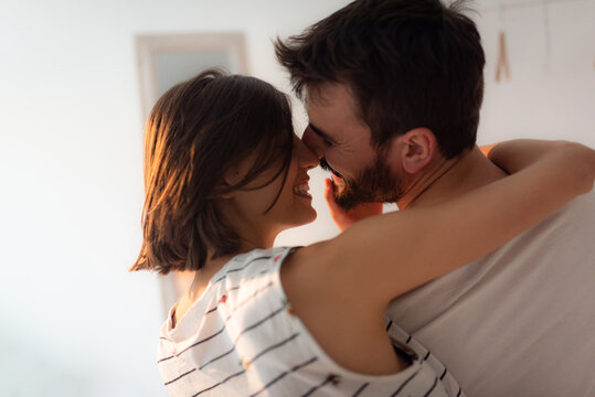 Young couple kissing and cuddling while siting on the bed.