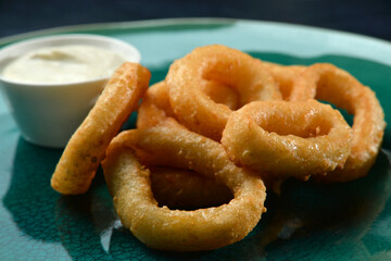 crunchy fried onion rings on plate with sauce closeup