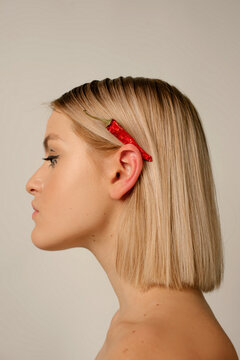 Portrait of sweet blonde girl with chilli pepper over her ear